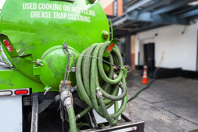 a professional plumber using a pump to empty a grease trap in Augusta